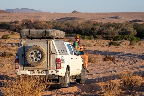 Tourist with off-road car on a sandy track, rock formation, Brandberg, Damaraland, Namibia