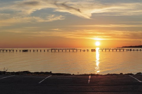 Sunset behind dilapidated fishing pier damaged by hurricanes on the Mississippi Gulf Coast in Long