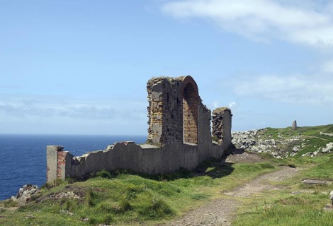A coastal ruin with a view of the blue sea and green meadows under a cloudy sky, Mining, Botallack,