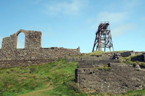 Mining ruins and a derelict tower stand on a grassy hill, engine room, mining, Botallack, Cornwall,