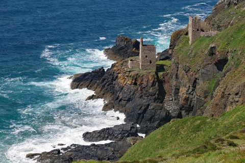 Historic ruins on a rocky cliff above the roaring sea and deep blue sky, engine room, mining,