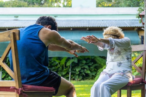 Physiotherapist assisting a senior woman with rehabilitation exercises in a vibrant home garden,