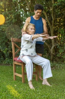 Senior woman practicing seated stretches with the assistance of a physiotherapist in a peaceful
