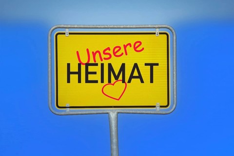 (Photomontage) Town sign with the inscription UNSERE HEIMAT and a heart