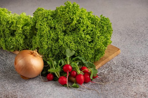 Green salad, onion and radish on a wooden board