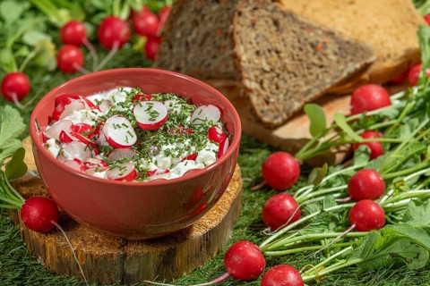 Cream cheese with radishes and herbs, next to slices of bread