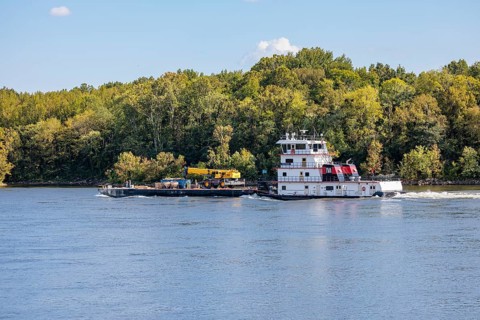 Tennessee Valley Authority tug boat Freedom pushing a barge with construction equipment upstream on