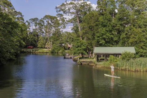 Young woman paddleboarding on the Magnolia River in Magnolia Springs, Alabama