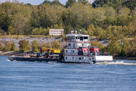Tennessee Valley Authority tug boat Freedom pushing a barge with construction equipment upstream on