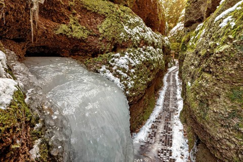 Frozen waterfall in a narrow gorge, lined with mossy rocks and snow, The Dragon Gorge near Eisenach