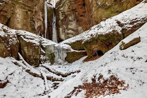 Snow-covered rocky landscape with icicles and a small cave, the Dragon Gorge near Eisenach in