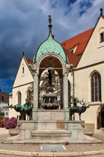 Magnificent fountain with figures in front of historic church, The town of Kempten im Allgäu