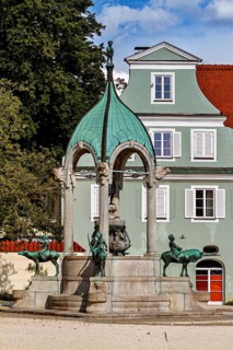 Historic fountain with green dome in front of a building with white windows in summer, The fountain