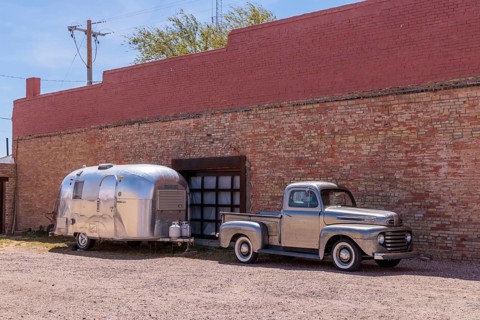 Silver painted classic fort pickup truck and a stainless steel Airstream camper travel trailer