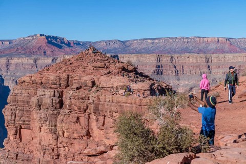 Visitors climb on rock formation rising above the canyon at Guano Point in Grand Canyon West near