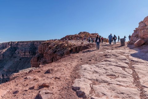 Tourists walk close to the edge of the canyon at Guano Point area of Grand Canyon West near Peach
