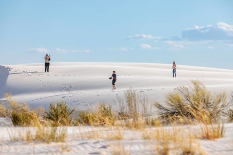 Man and teen children playing frisbee on the gypsum dunes at White Sands National Park near