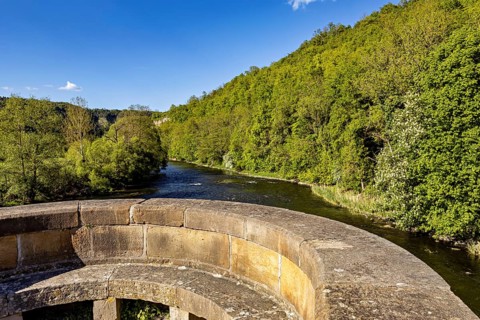 Stone bridge with a view of a river and green hills in the background, view from the historic Werra
