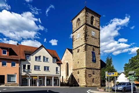 Central church tower in the village with surrounding buildings and streets under a blue sky, The