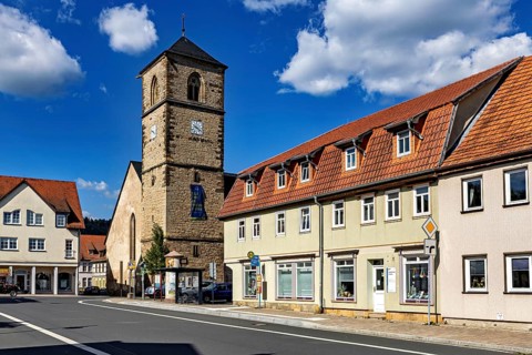 Church tower next to village buildings under a cloudy blue sky, The steeple of the Protestant