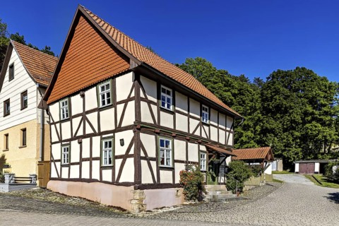 A picturesque half-timbered house with red roof tiles under a bright blue sky in the countryside,