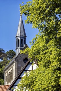 Top of a church with half-timbering and surrounding greenery against a clear sky, The church of the