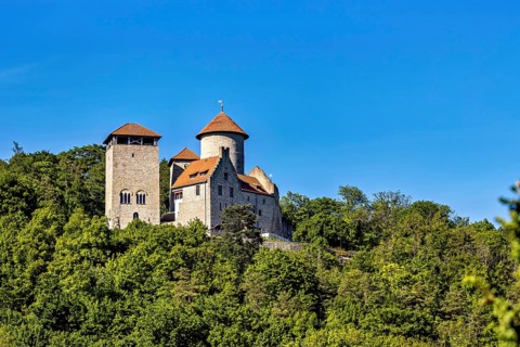 Old castle on a wooded hill in sunny weather and clear skies, Normannstein Castle near Treffurt in
