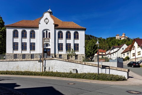 A white building with red tiled roofs in a small, quiet village under a blue sky, the town of