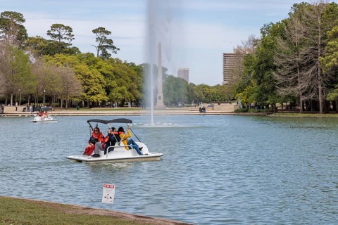 Young family piloting a pedal boat on Lake McGovern at Hermann Park in downtown Houston, Texas
