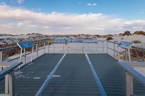 Signage informs visitors about dunes and wildlife along the Interdune Boardwalk over the gypsum