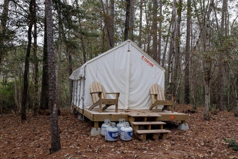 Propane tanks outside a Tentrr glamping tent on a raised platform with a wooden porch at Clarko