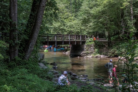 Visitors cross Trail Bridge to get upstream with inflatables for tubing along Deep Creek in the