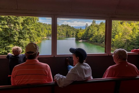 Great Smoky Mountains Railroad passengers looking out the windows of the open air train car while