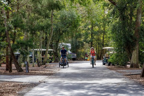 Man and woman ride bicycles through a camping loop at Fort Wilderness campground at Walt Disney