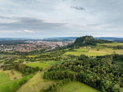 Luftbild vom Vulkankegel Hohentwiel mit der Burgruine, dahinter die Stadt Singen am Hohentwiel,