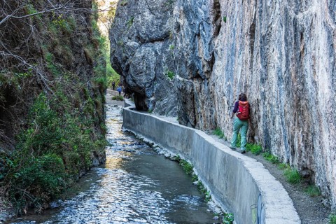 Woman on narrow hiking path Los Cahorros de Monachil, along the Rio Monachil river, narrow path in