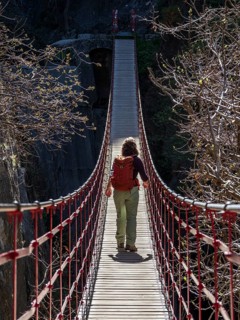 Woman on suspension bridge, hiking path Los Cahorros de Monachil, along the Rio Monachil river,