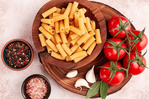 Pasta ingredients spread out, on a wooden surface, with tomatoes and spices, ready to cook, there