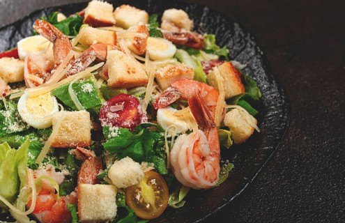 Caesar salad with tiger prawns, shrimp salad, lettuce leaves, quail eggs, cherry tomatoes, parmesan