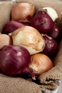 Various varieties of onions, in a basket, on a wooden surface, rustic style, close-up, no people
