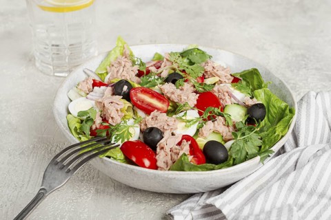 Salad with canned tuna, vegetable salad with quail eggs, lettuce and romaine leaves, red onion,