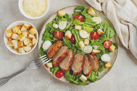 Caesar salad, with duck breast, on a light plate, on a light background, homemade, no people