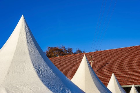 A row of pointed tents in front of a roof structure