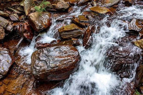 Small stream of clear water flowing between the rocks in Minas Gerais, Minas Gerais, Brazil