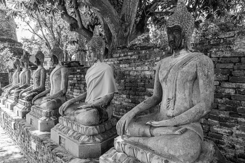 Stone Buddha statues sitting in a row, historic Buddhist temple complex, black and white photo,