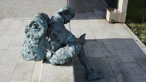 Stone figure of a seated pilgrim with backpack in the sun, pilgrims on the Caminho Portugues,