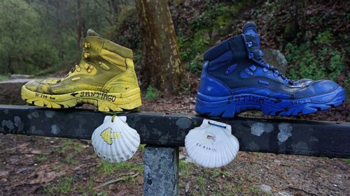 Two hiking boots on a railing decorated with shells, as a guide to Santiago and Fatima, make a