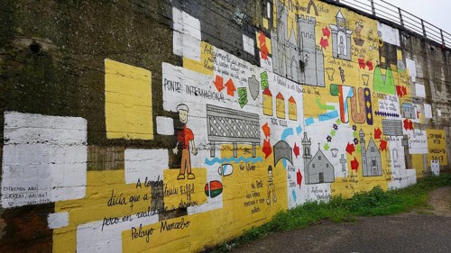 Large-scale wall painting with colorful symbols and texts depicting the Camino de Santiago on the