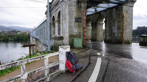 Old stone bridge, with arched construction, a hiking backpack leaning against a railing during a