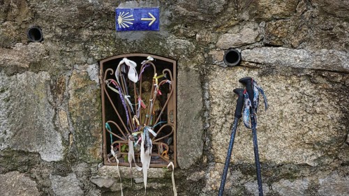 Window opening in a stone wall with pilgrim sticks, decoration, sign with scallop as a guide on the